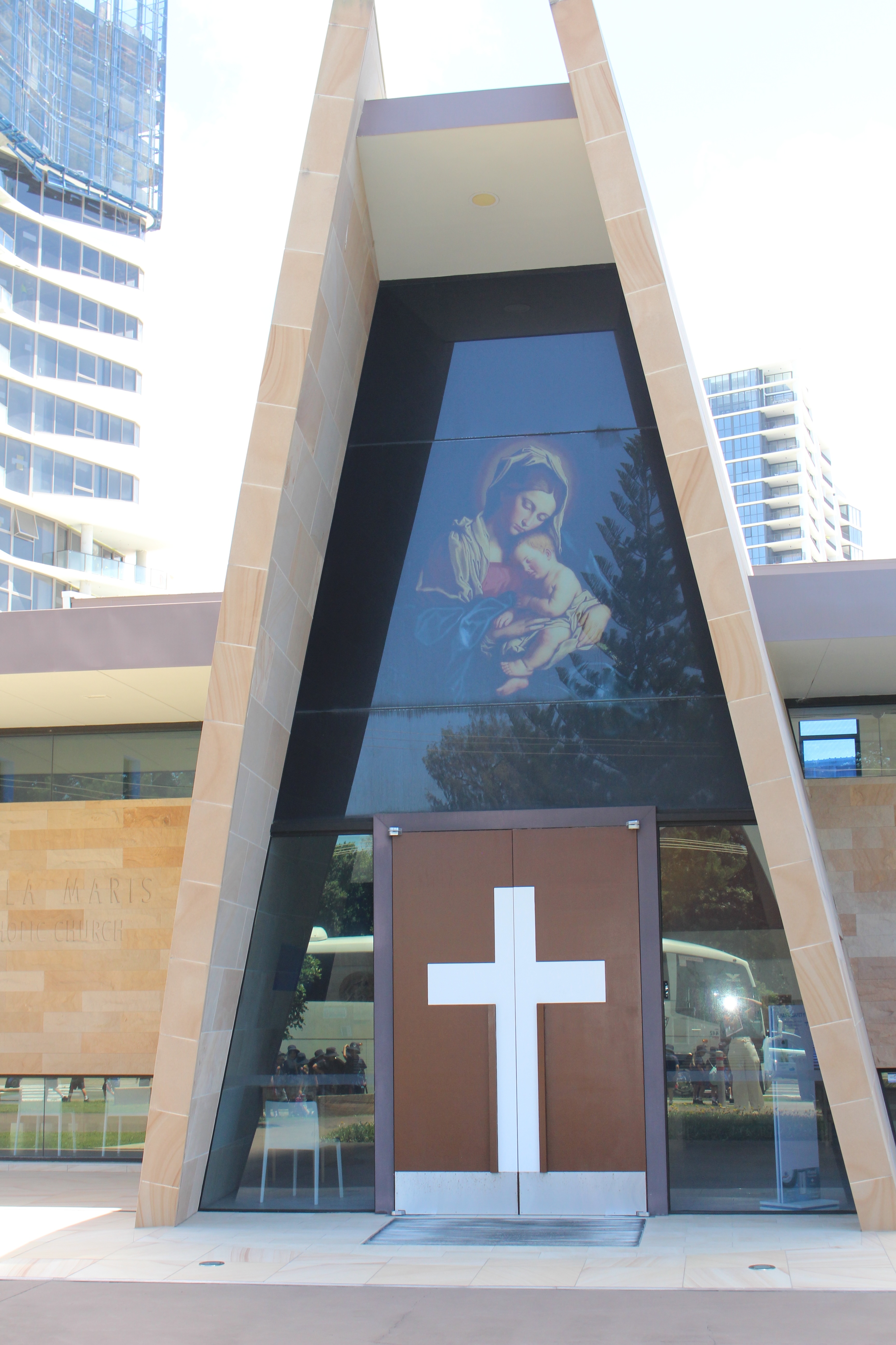 Modern chapel entrance with large cross on the doors and artwork of Mary holding a child above the doorway