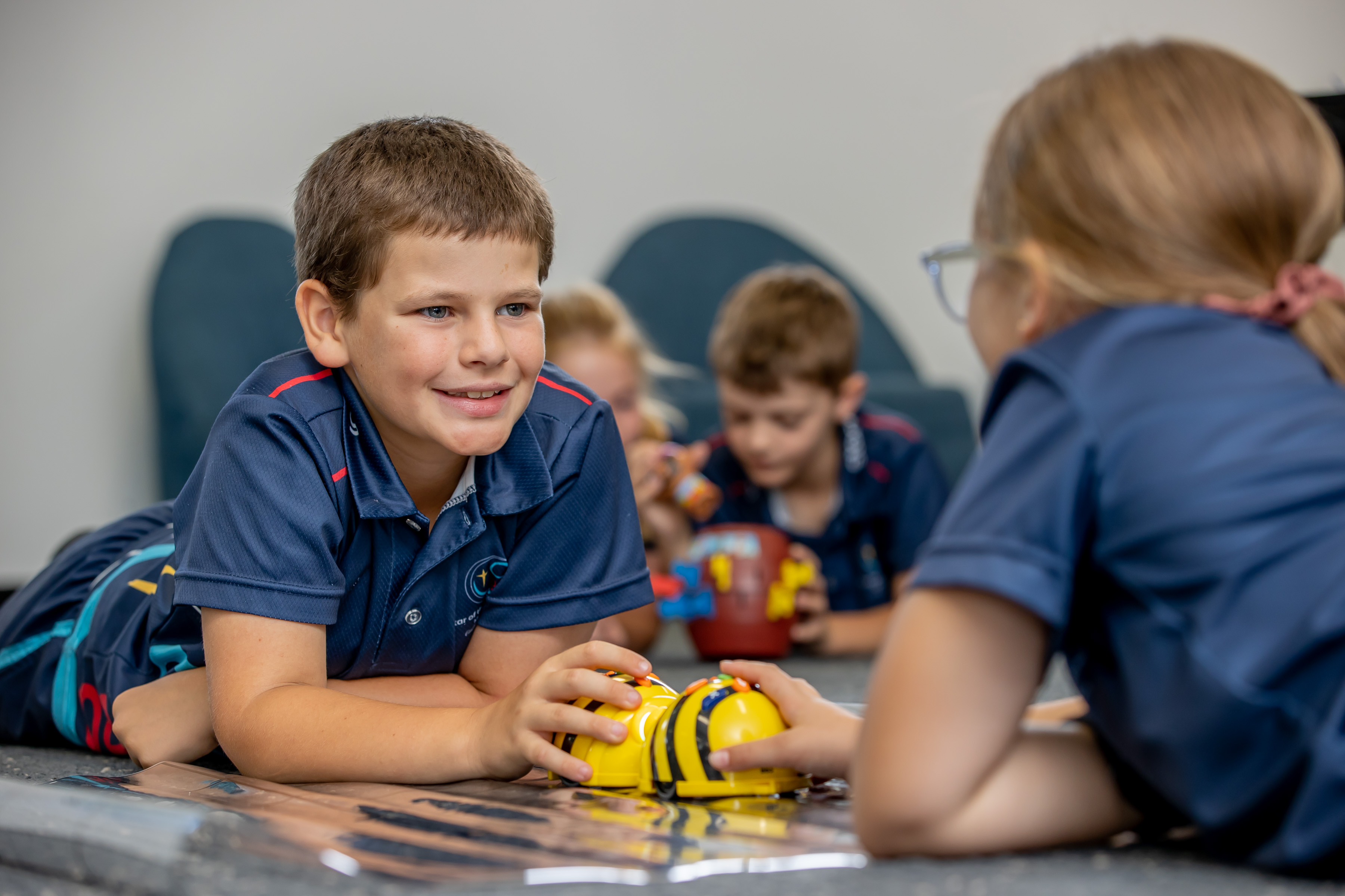 Students collaborating at a table using a small robot during a classroom activity